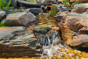 Backyard waterfall into rocky natural pond stream.